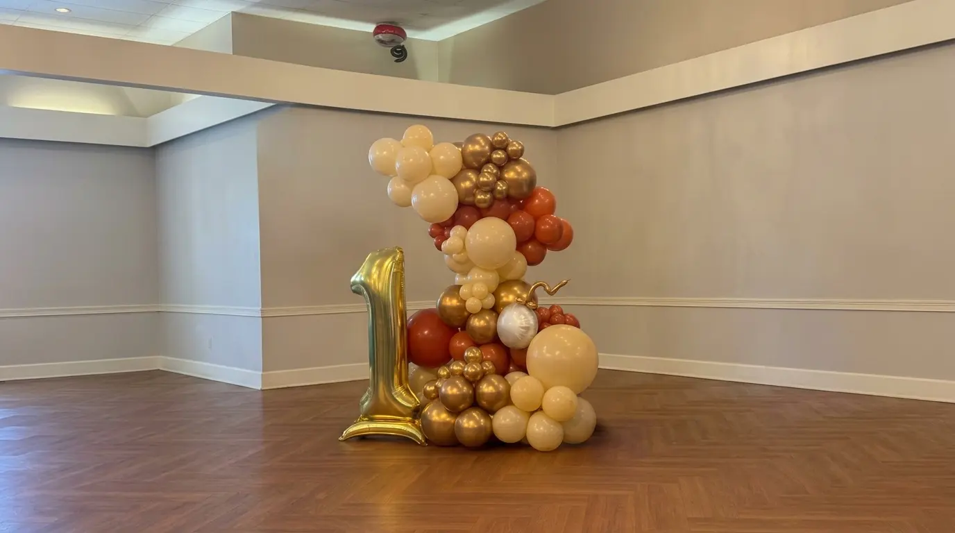 Organic cream, gold and terracotta balloon column with a gold number 1 foil balloon for a first birthday in an event hall, New Jersey