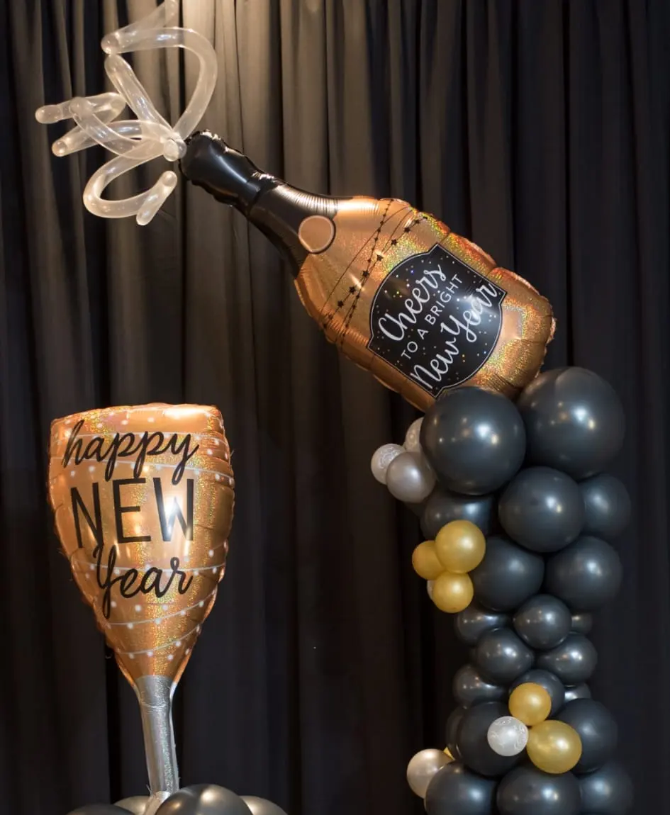 Black, gold and silver balloon columns topped with a Cheers champagne bottle pouring into a Happy New Year glass, New Jersey