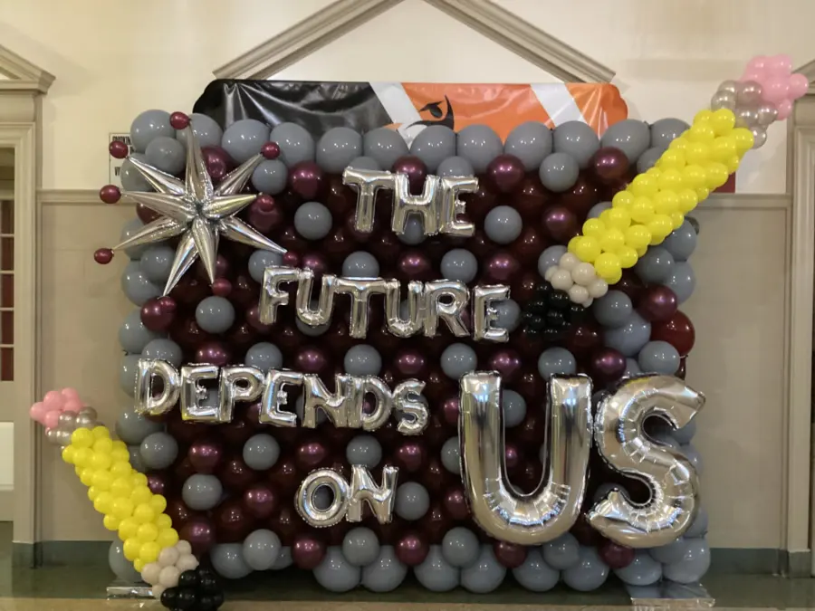 Maroon and gray balloon wall with silver foil letters and pencil balloons at a school event, New Jersey