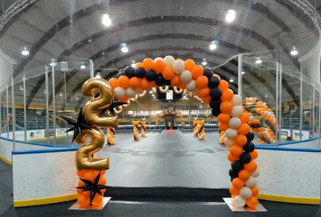 Orange, white and black graduation balloon arch with gold 22 foil numbers at an ice rink, New Jersey
