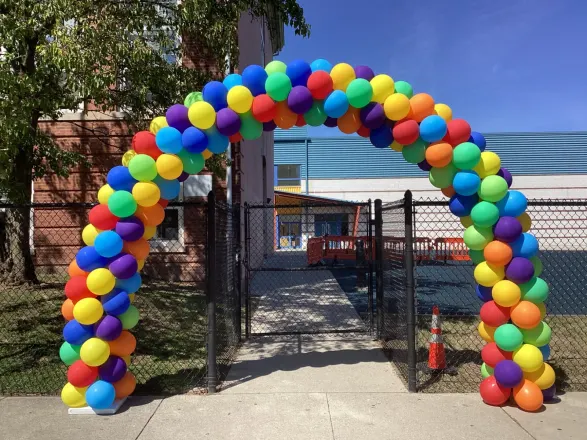 Rainbow balloon arch in red, orange, yellow, green, blue and purple over a school gate entrance, New Jersey