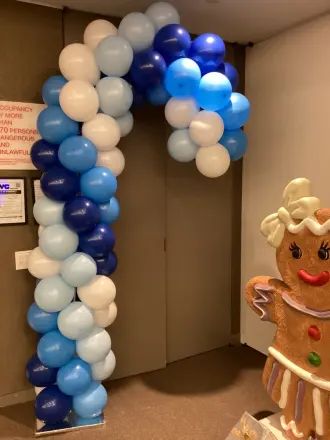 Blue and white candy cane balloon arch beside a gingerbread figure at a Christmas event, New Jersey
